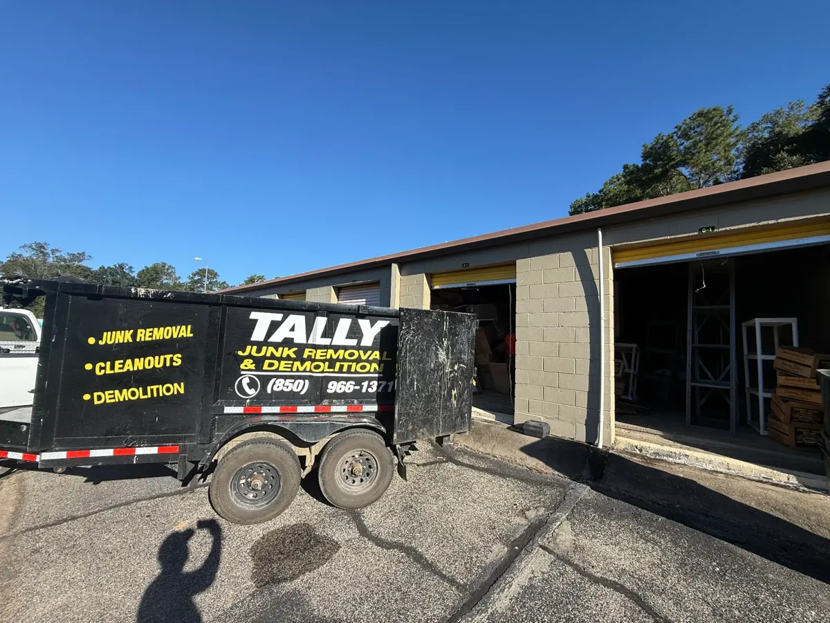 Tally Junk Removal dump trailer backed up to the open storage unit during the cleanout