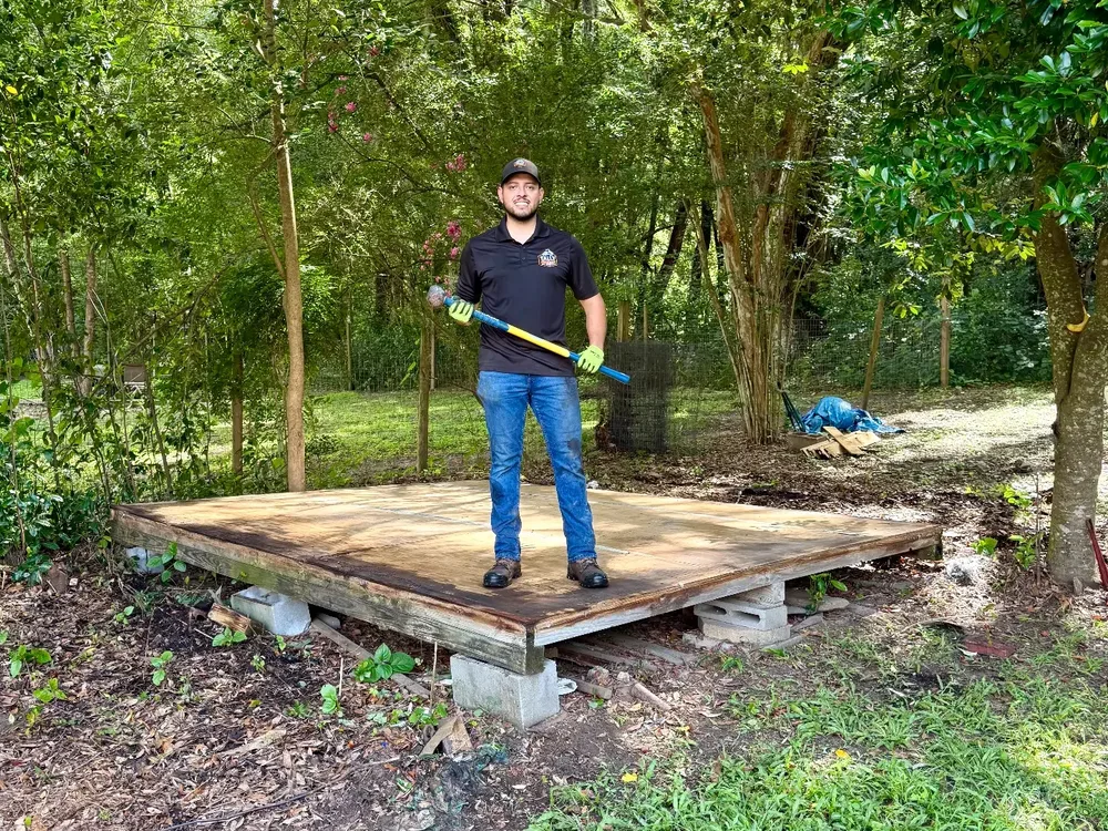 Tally Junk Removal owner standing on a cleared shed slab after a backyard shed demolition