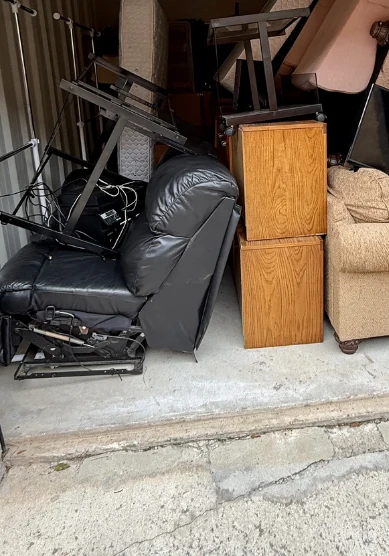 Storage unit packed with a recliner, mattress, wooden cabinets, and a sofa before cleanout