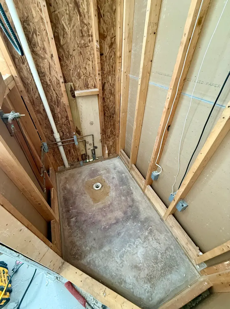 Shower stripped to studs and concrete slab after tile removal