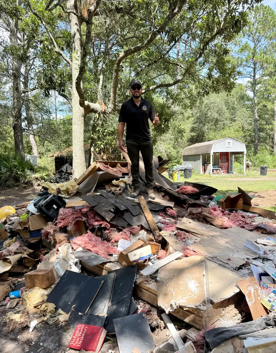 Tally Junk Removal owner standing on the shed demolition debris pile