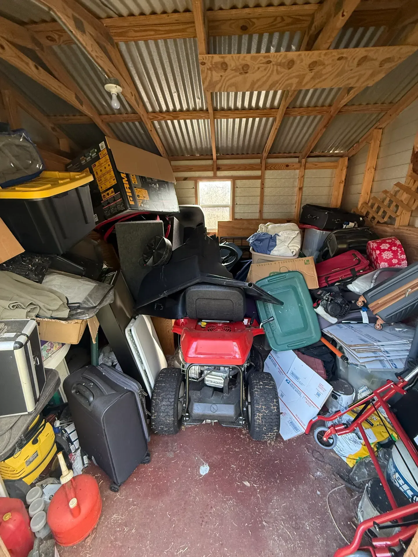 Backyard shed packed floor to ceiling with tools, bins, and yard equipment before the contents were emptied out