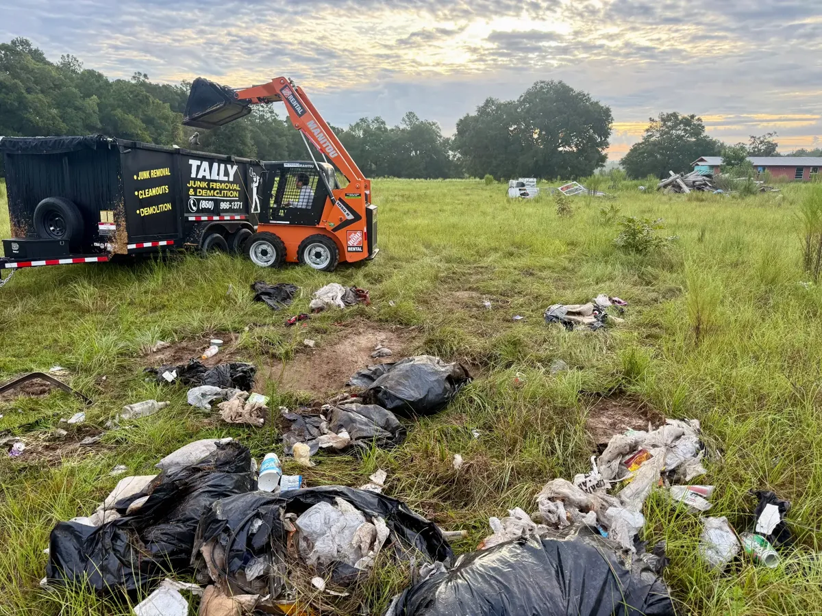 Bagged trash and debris scattered across a grassy lot before cleanup