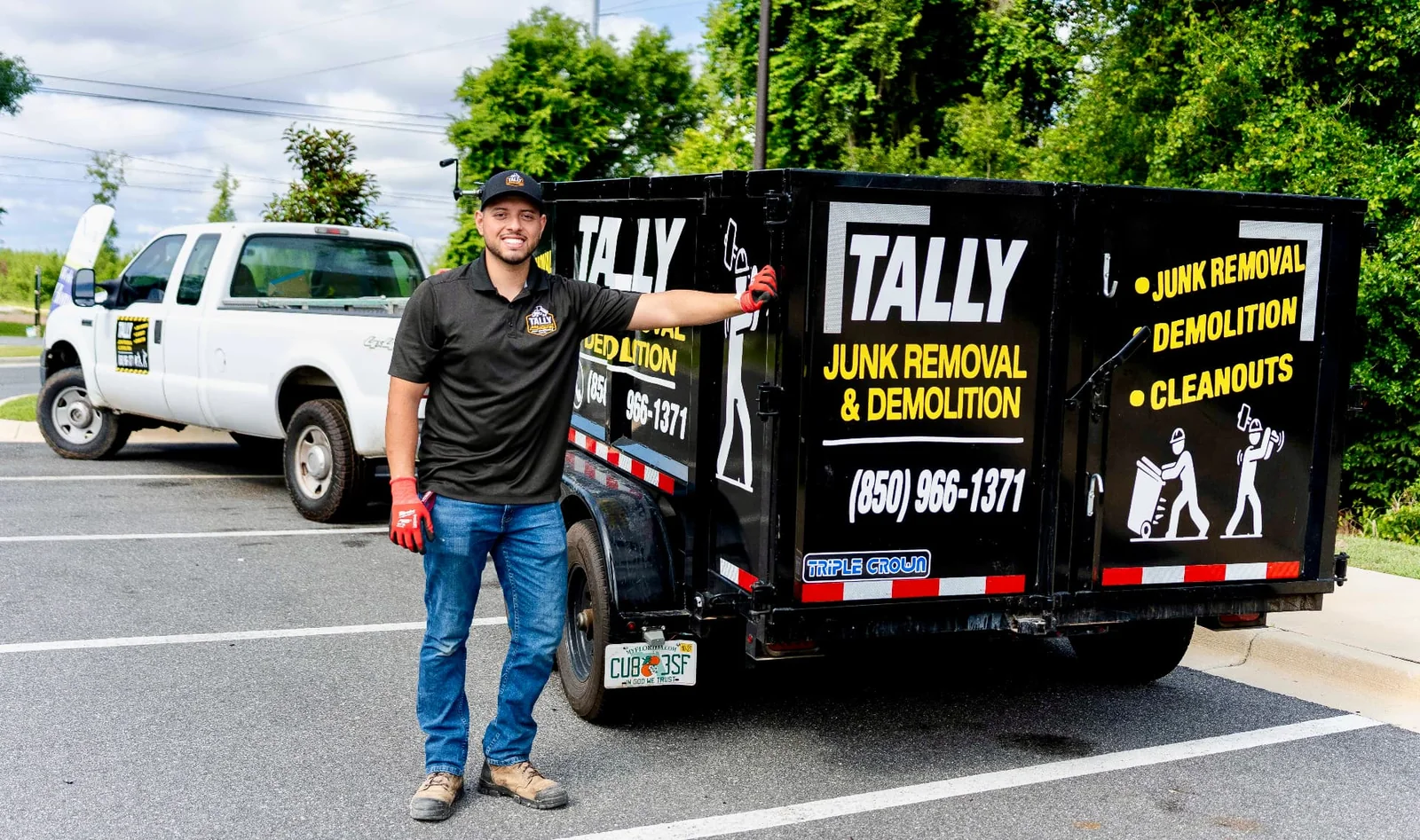 Owner of Tally Junk Removal and Demolition standing beside the black branded dump trailer and white pickup truck