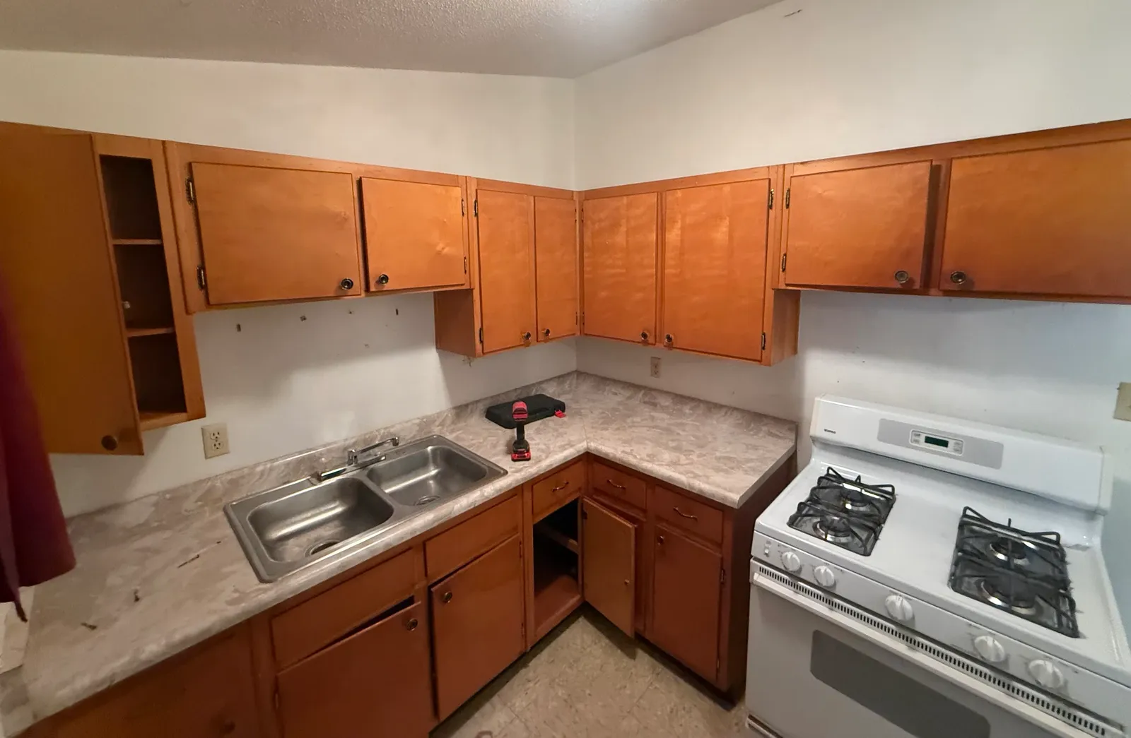 Wood kitchen cabinets, counters, sink, and white range before tear-out