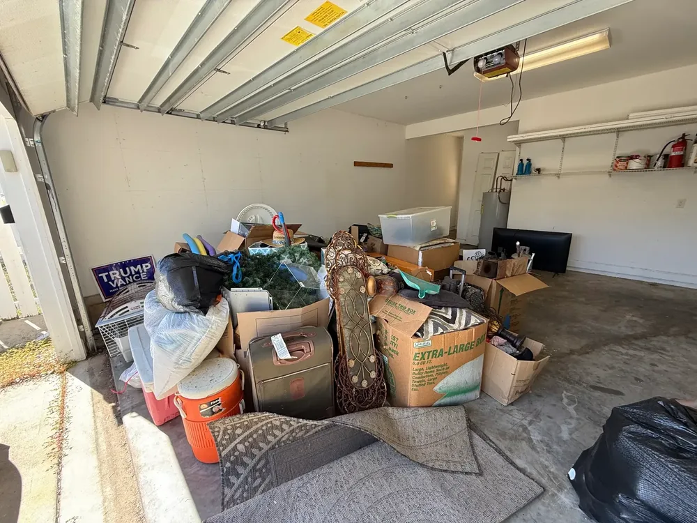 Garage stacked with boxes, bags, and household items before a property cleanout