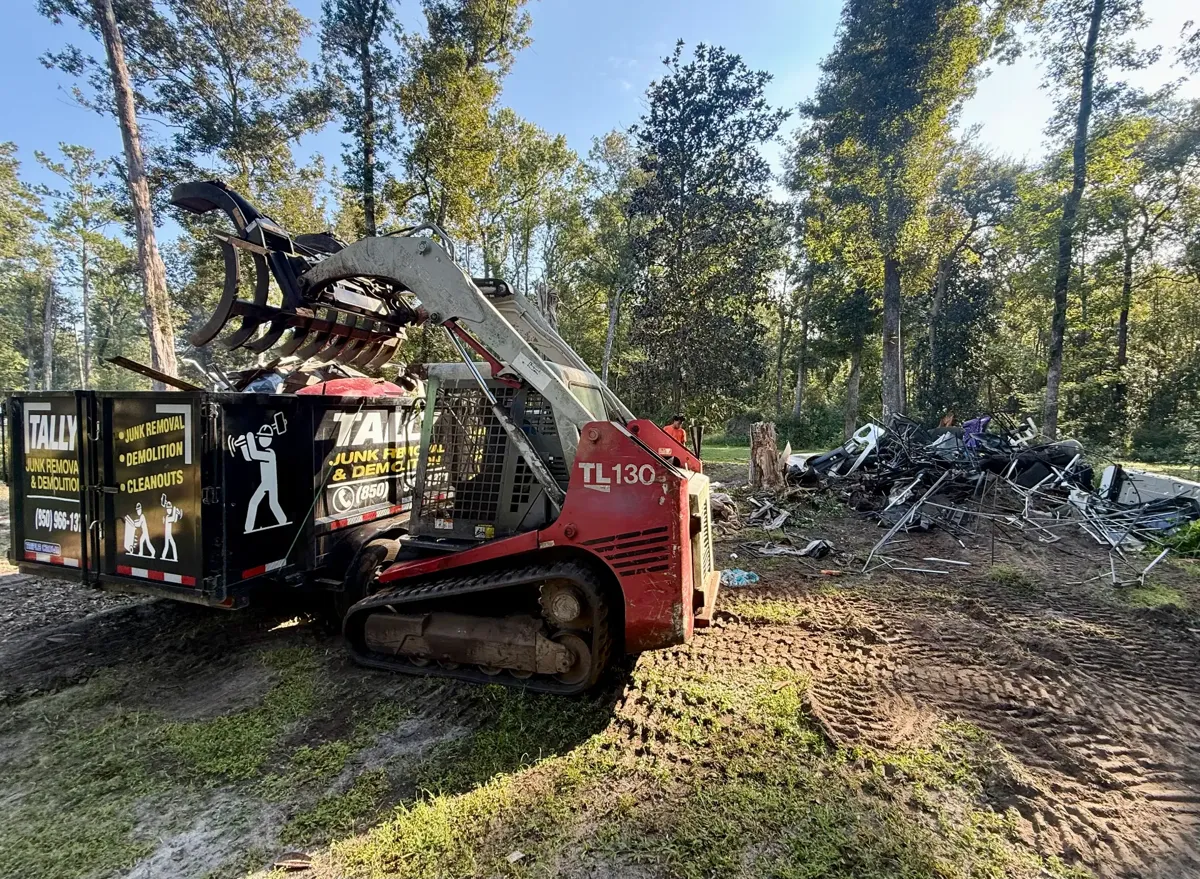 Track loader beside the Tally Junk Removal trailer during a lot cleanup